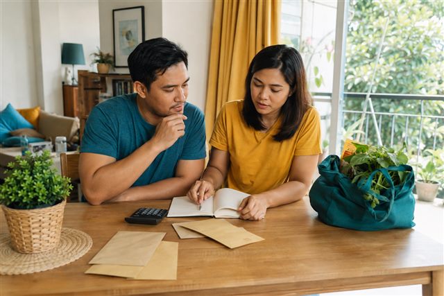 A couple reviewing a notebook and calculator at their dining table